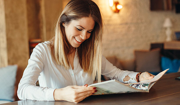 eine Frau hält eine Zeitschrift in der Hand und lächelt