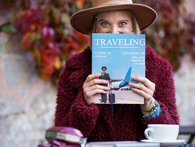 eine Frau zeigt lächelnd den Reisekatalog, den sie sich anschauen möchte